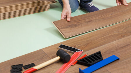 worker installing laminate flooring in a new house